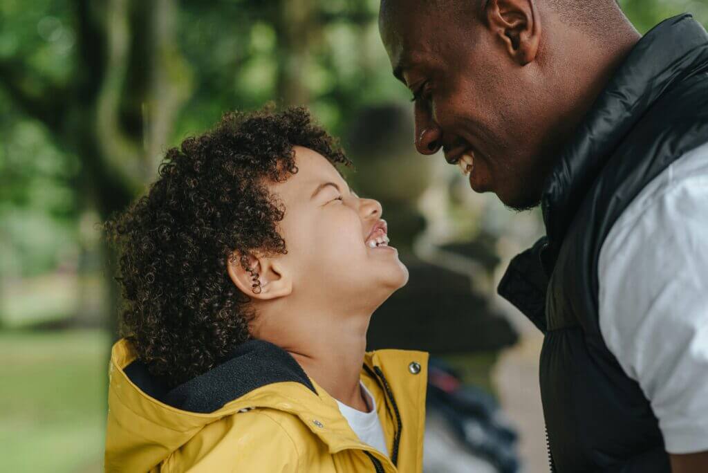 A parent and child are smiling at each other after working with an online child therapist in North Carolina or South Carolina to help the child with coping strategies to manage big feelings and emotions. This child's behaviors have calmed down, and they are able to be happy and enjoy life again.