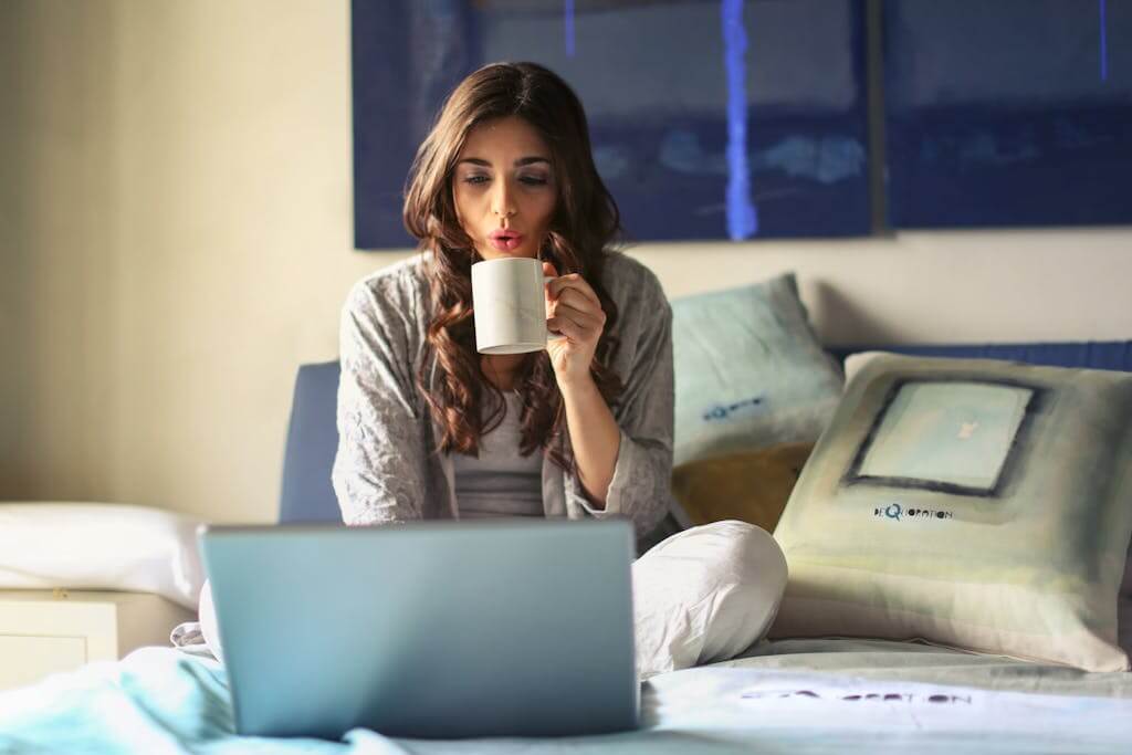 A woman who lives in Charlotte, NC sits on Bed Uses Grey Laptop to schedule an online Telehealth therapy appointment with Eleena Hardzinski. Online Counseling services are provided in North Carolina and South Carolina. Schedule and online therapy appointment today!