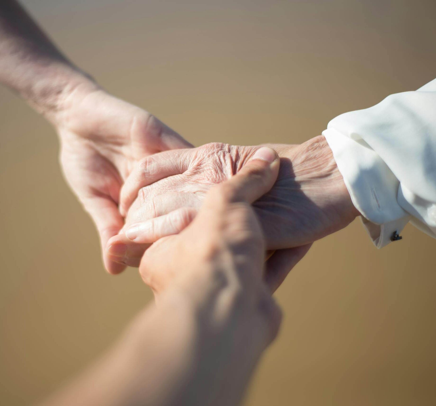 Gentle close-up of intergenerational hands holding, symbolizing connection and care.