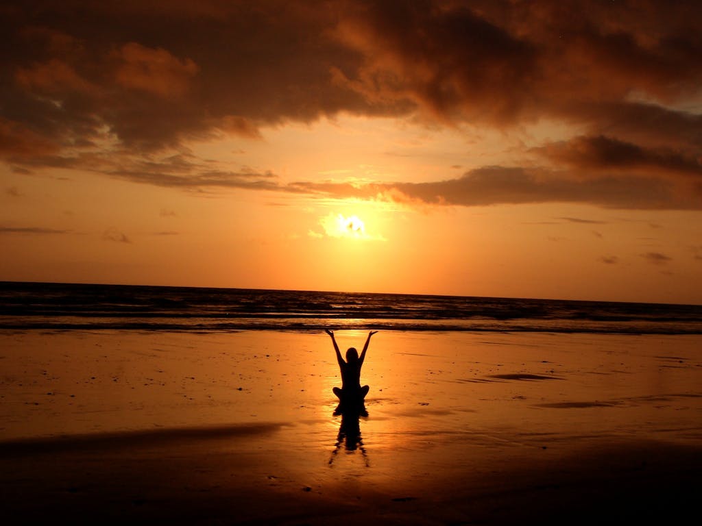 Silhouette of woman at sunrise, Hilton Head | Brainspotting Charlotte NC | Virtual trauma therapy Rock Hill SC | Healing after trauma Raleigh NC | 28207 | 29466 | 27517 | Woman greets sunrise by the ocean near Hilton Head, SC. Start your healing journey with brainspotting therapy in Charlotte or Rock Hill. Book a virtual session today.