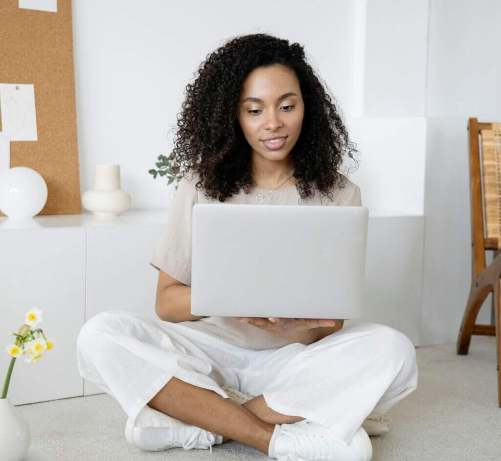 Woman sitting comfortably with a laptop during an online therapy session, showing how virtual counseling works for moms in Matthews, NC