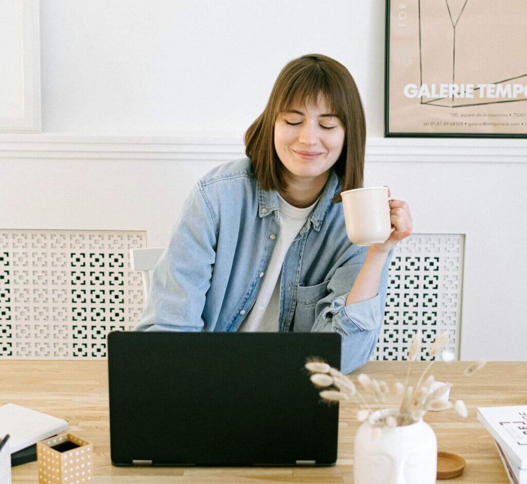 Woman sitting at home in Greenville NC looking happy before beginning online therapy with Mosaic Reflections | ADHD Therapy | Therapy for Trauma | Brainspotting