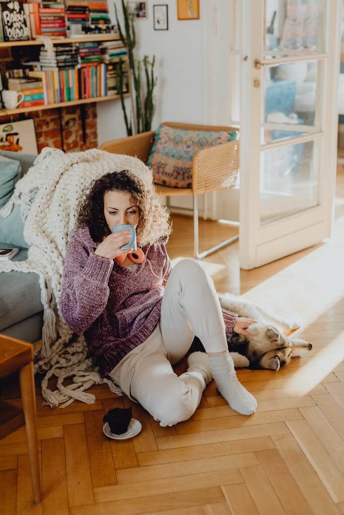 Woman sitting thoughtfully at home in Durham NC before beginning online therapy with Mosaic Reflections | Therapy for Trauma | Anxiety Therapy | Brainspotting Therapy 